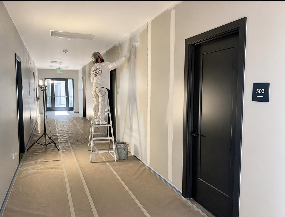 Painter finishing a residential corridor during a common area renovation